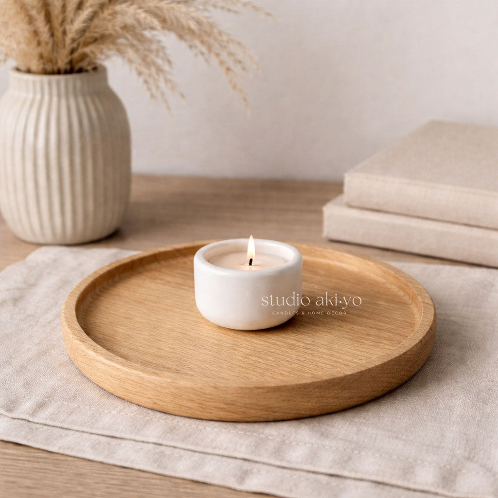 Wooden tray with a white candle on a neutral background, featuring 'studio akito' branding.