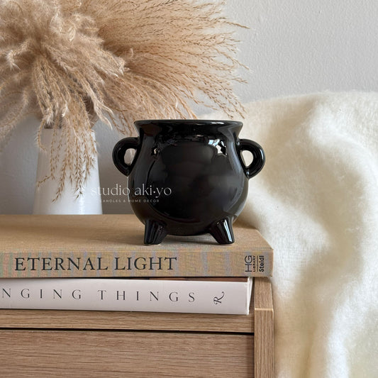 Black ceramic pot on books with decorative elements in the background
