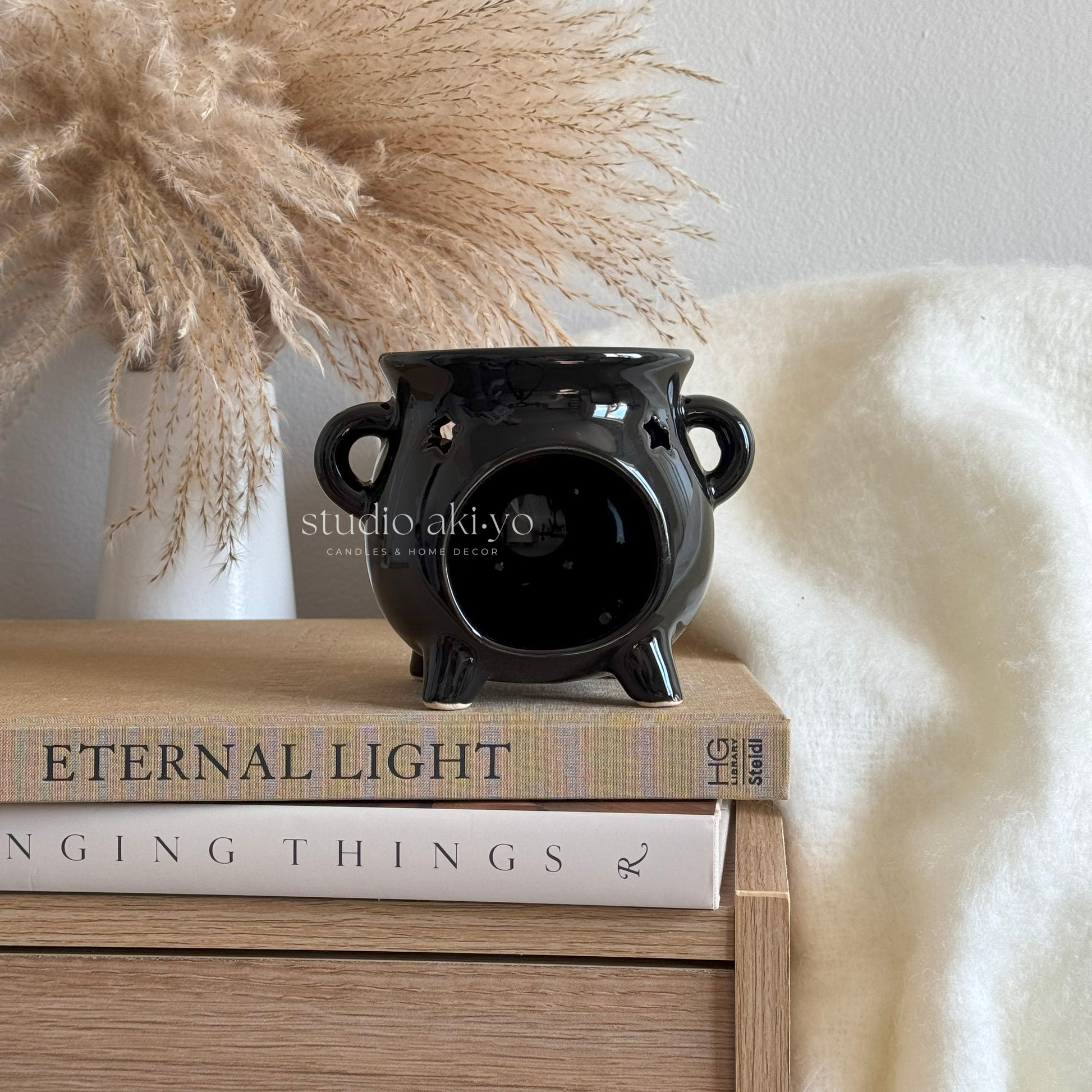 Black ceramic vase on a stack of books with decorative elements in the background