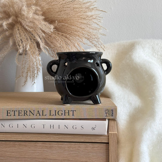 Black ceramic vase on a stack of books with decorative elements in the background