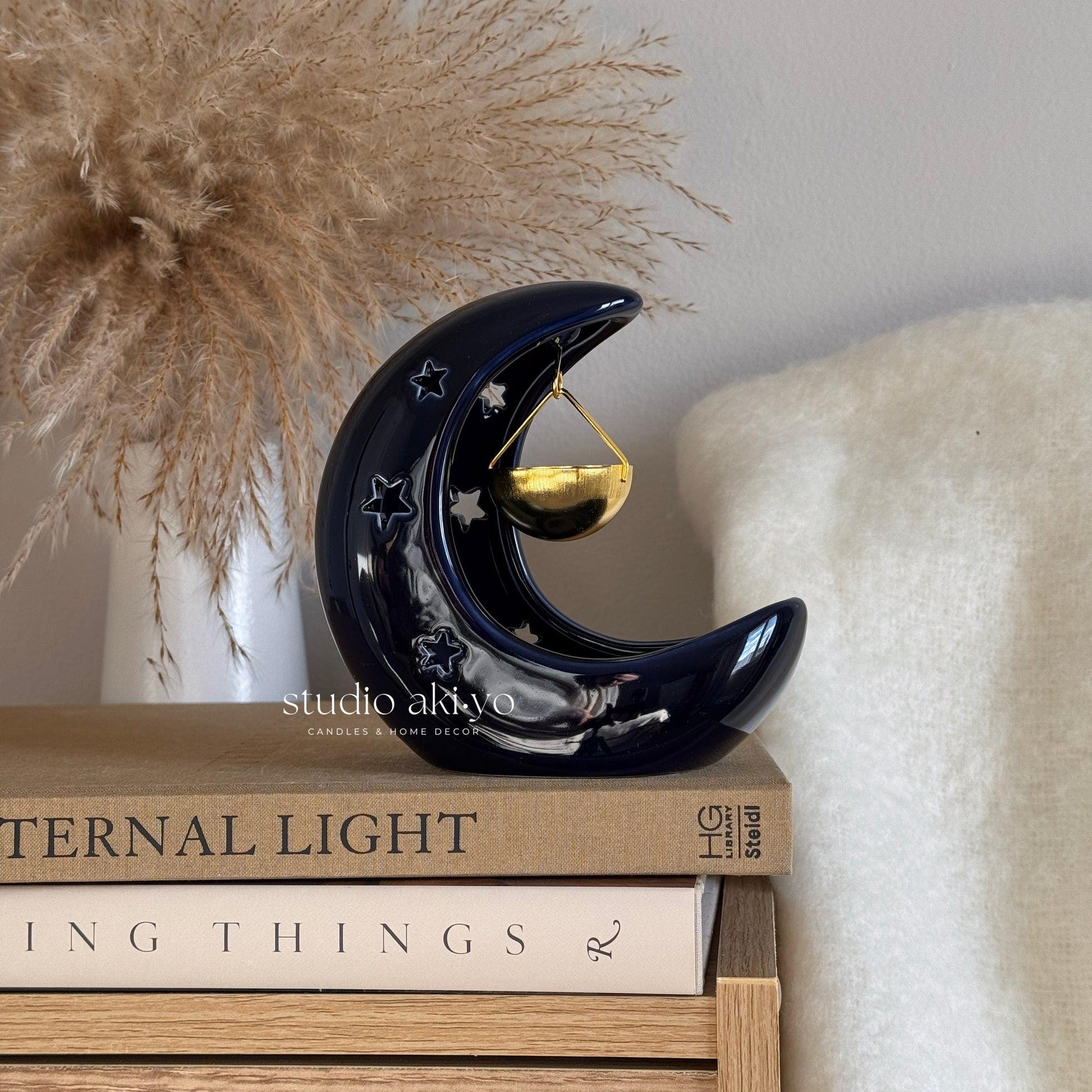 Decorative moon-shaped object on books with a neutral background