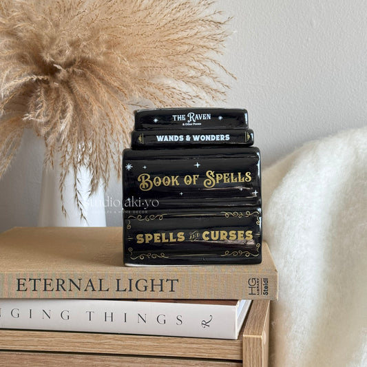 Hocus Pocus stack of books wax melt burner with decorative titles on a wooden surface, with a neutral background.