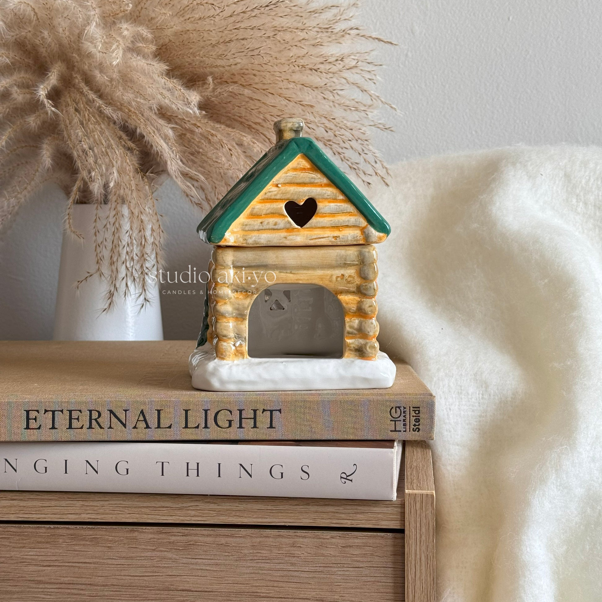 Winter cabin ski chalet wax burner on a stack of books with a soft white background