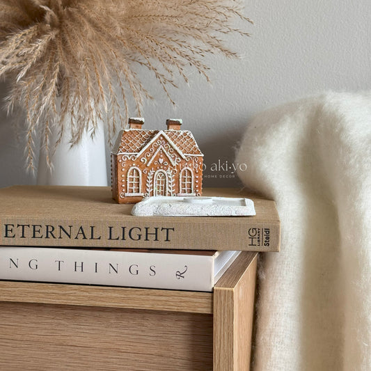 Brown Gingerbread Incense Cone Holder on a stack of books with decorative elements in the background.