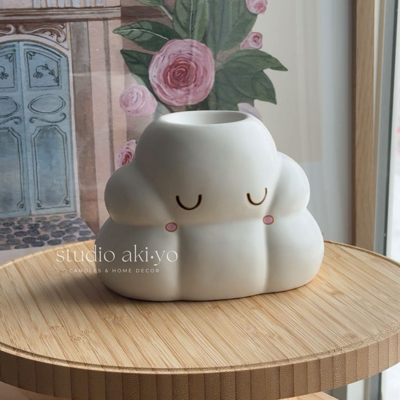 Cute cloud-shaped vase with a smiling face on a wooden table, brand 'studio akiyo' visible.