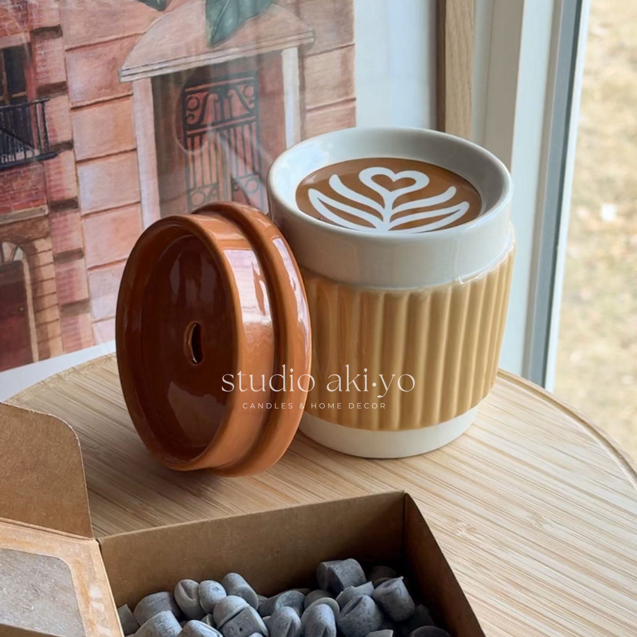Ceramic container with lid featuring a heart-shaped latte art design on a wooden surface.