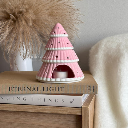 Pink ceramic tree-shaped lantern on books with a neutral background