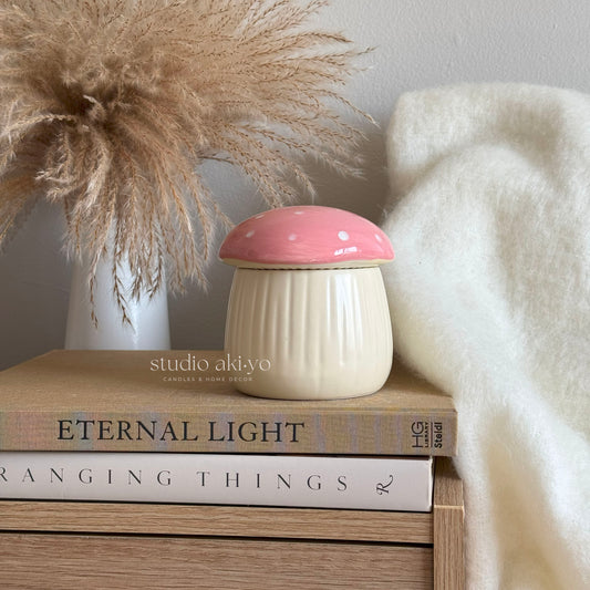 Small white and pink ceramic container on books with decorative elements in the background