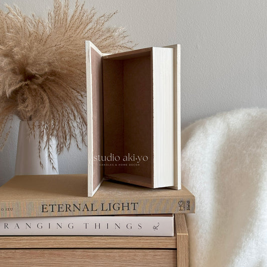 Decorative box with 'studio akiyo' branding on a wooden surface with books and decorative elements.