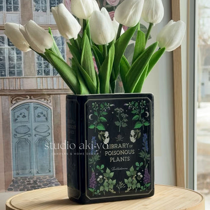 Vase with white tulips on a table in a room with large windows.