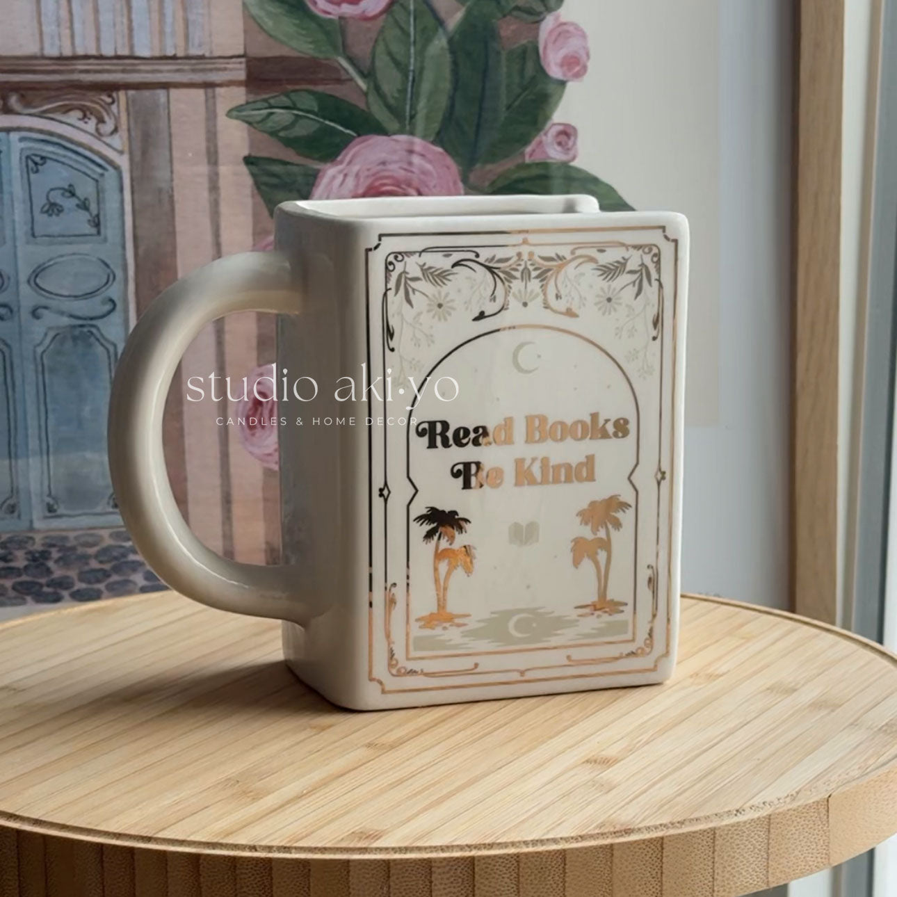 Mug with book design and 'Read Books To Kind' text on a wooden surface.