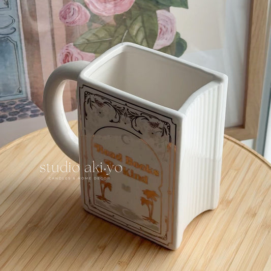 Square mug with decorative design on a wooden surface, brand 'studio aki.yo' visible