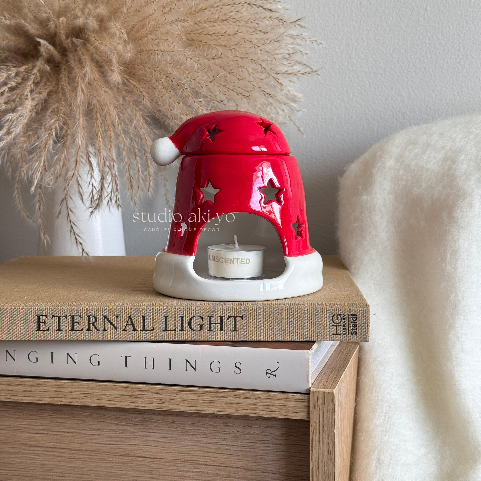 Red ceramic lamp with star design on top of books, featuring 'studio akiyo' branding.