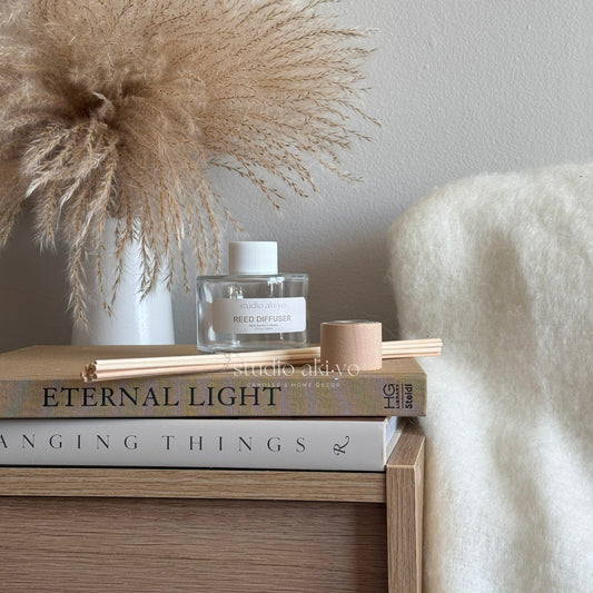 Flower Market scented reed diffuser with books and decorative elements on a wooden surface
