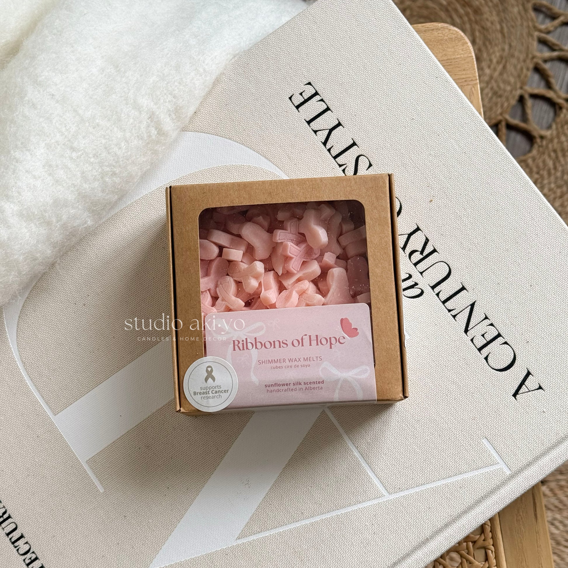 Box of pink wax melts labeled 'Ribbons of Hope' on a textured surface with 'studio artivo' branding.