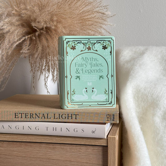 Book titled 'Myths, Fairy Tales, & Legends' on a stack of books with decorative elements.