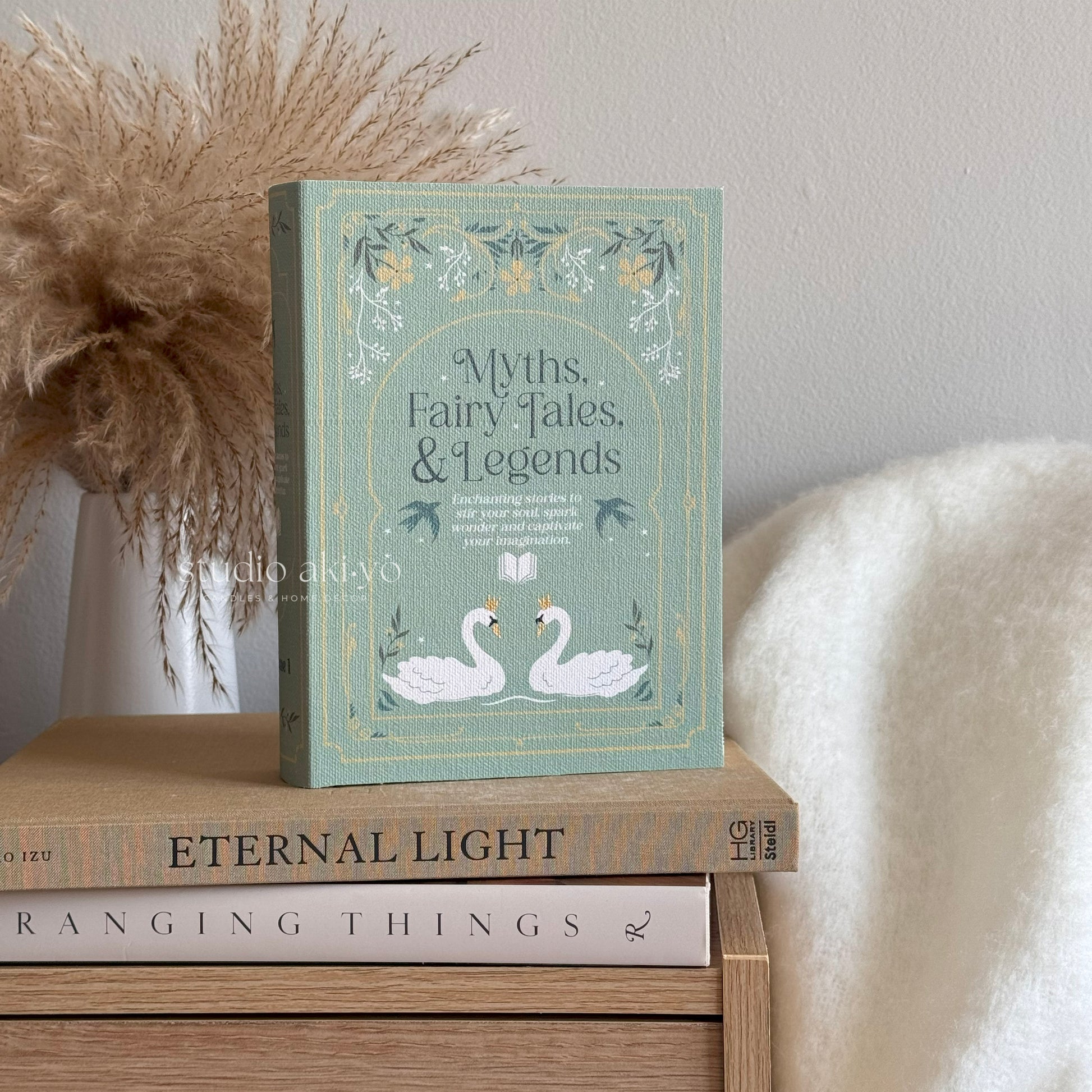 Book titled 'Myths, Fairy Tales, & Legends' on a wooden surface with decorative elements.