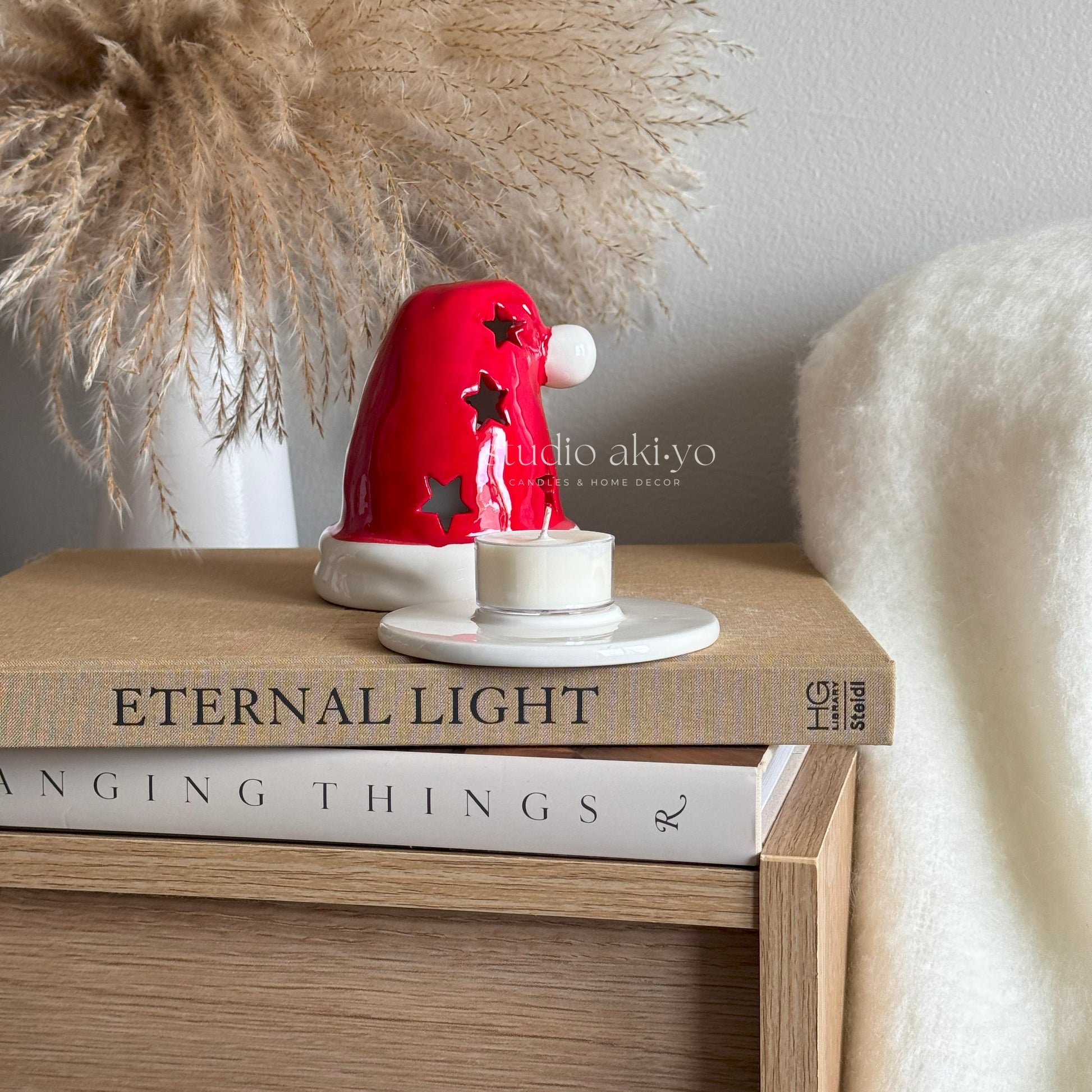 Decorative red and white lamp on a stack of books with 'Eternal Light' and 'Angling Things' visible.
