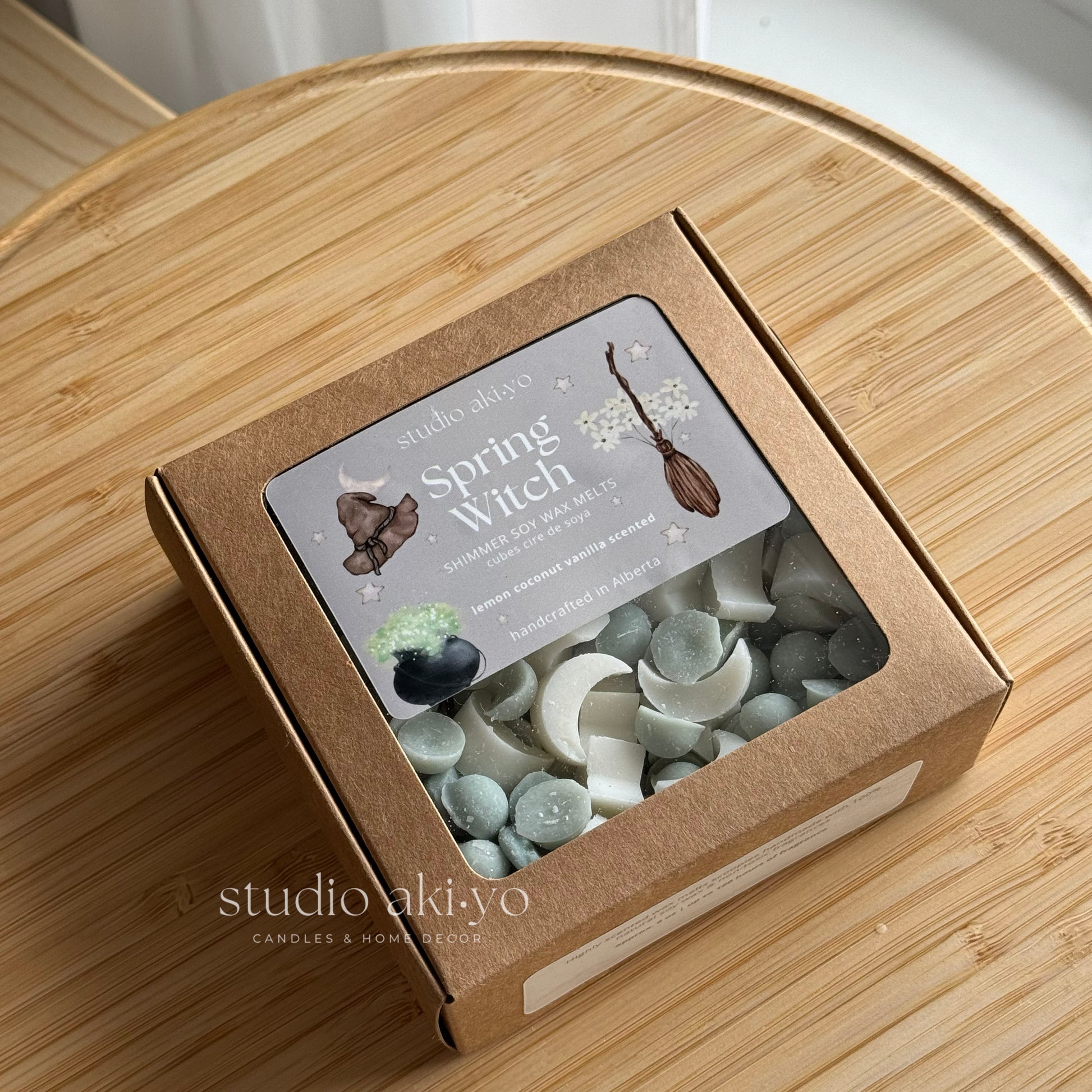Box of 'Spring Witch' candles with decorative elements on a wooden surface