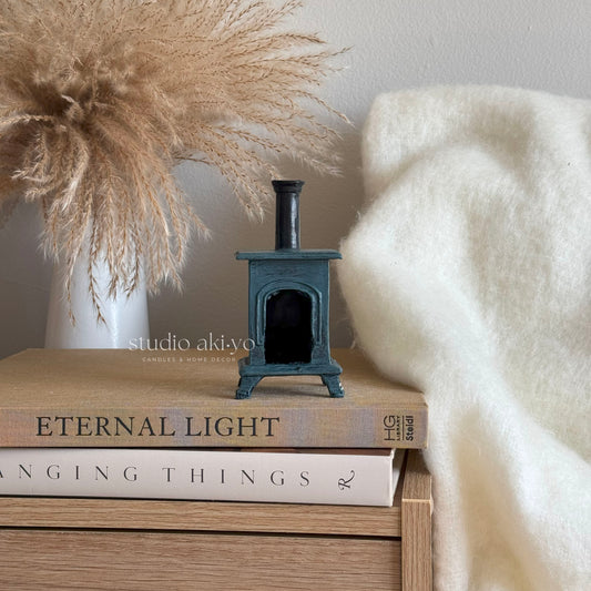 Small black stove incense cone holder on books with decorative pampas grass and white blanket
