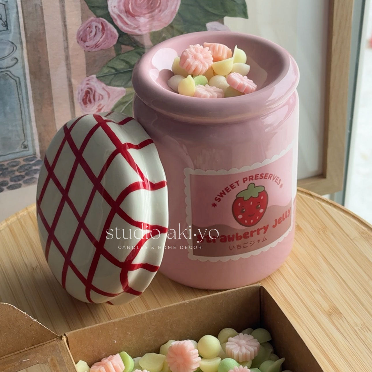 Pink jar with strawberry design and jelly candies on a wooden surface, with 'studio akiyo' branding.