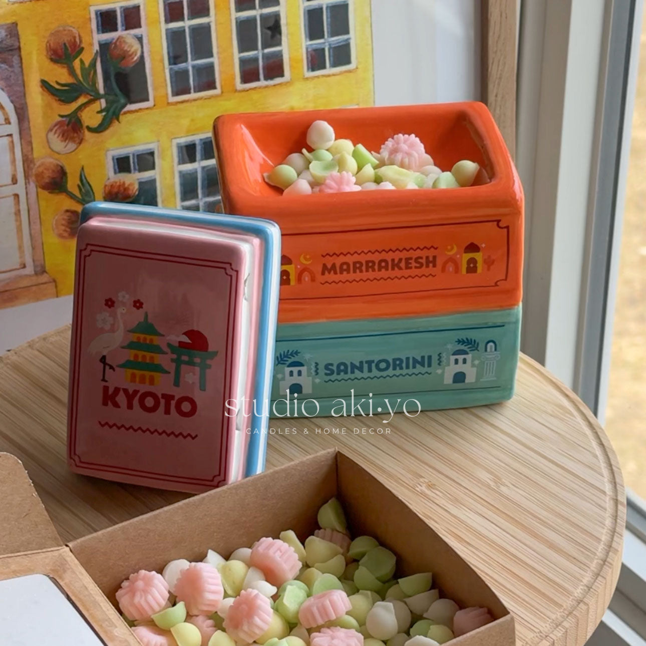 Colorful toy boxes with miniature landscapes and candy on a wooden surface.