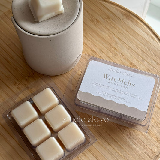 Studio Akiyo wax melts clamshell in their packaging on a wooden surface. Made from natural soy wax and clean burning fragrances.