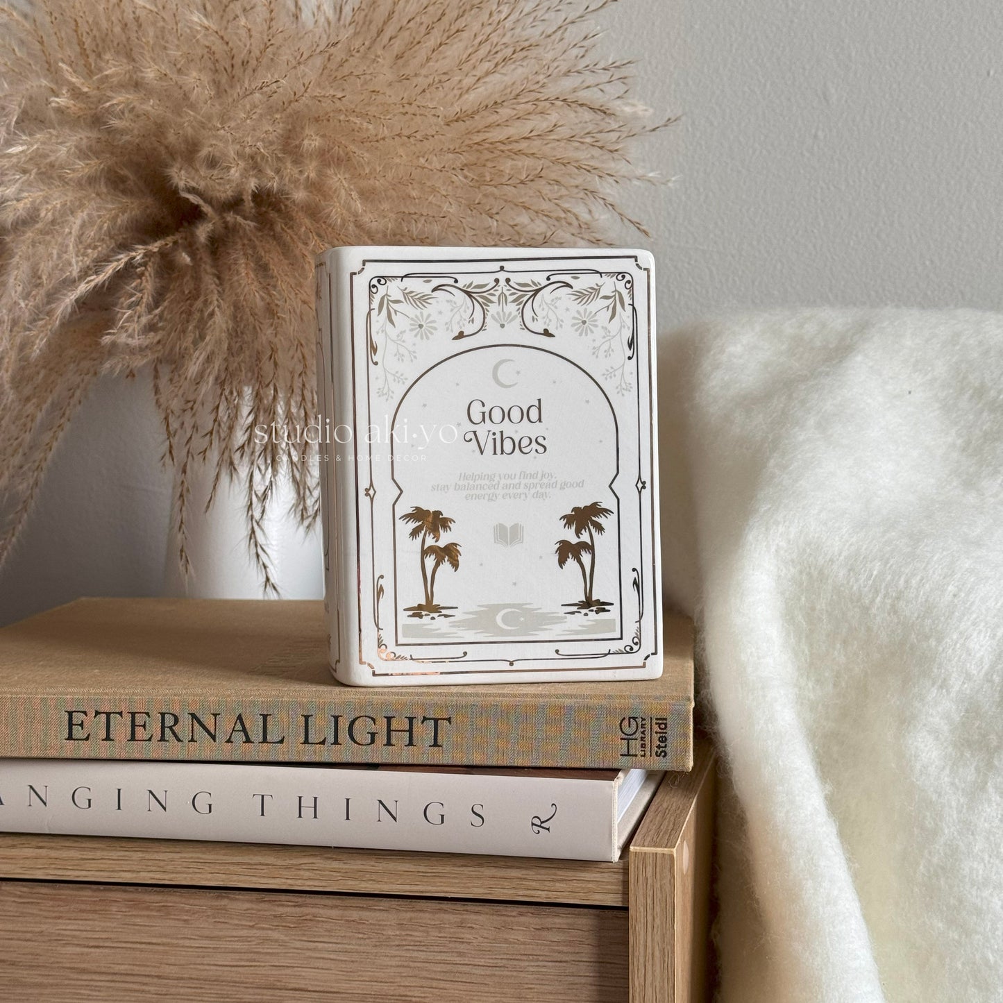 Stack of books with a decorative book titled 'Good Vibes' on top, against a neutral background.