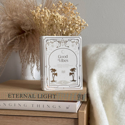 Decorative container with 'Good Vibes' text on a stack of books with a soft background