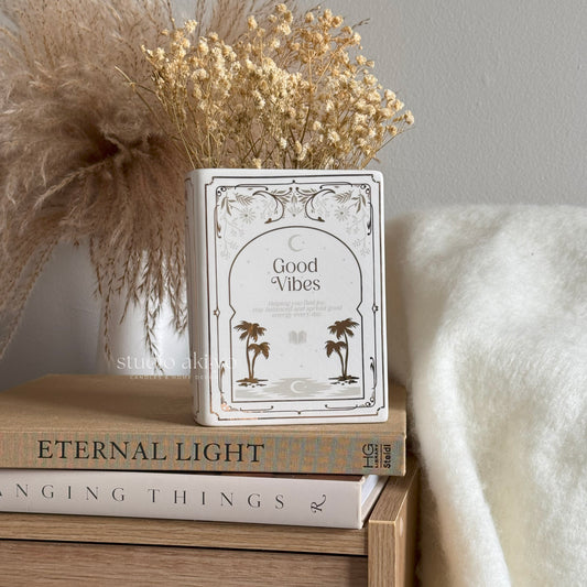 Decorative container with 'Good Vibes' text on a stack of books with a soft background