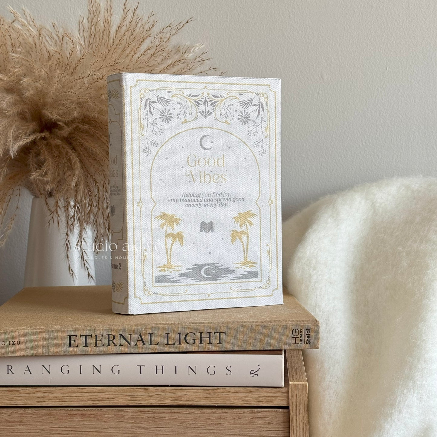 Book titled 'Good Vibes' on a wooden surface with decorative elements.
