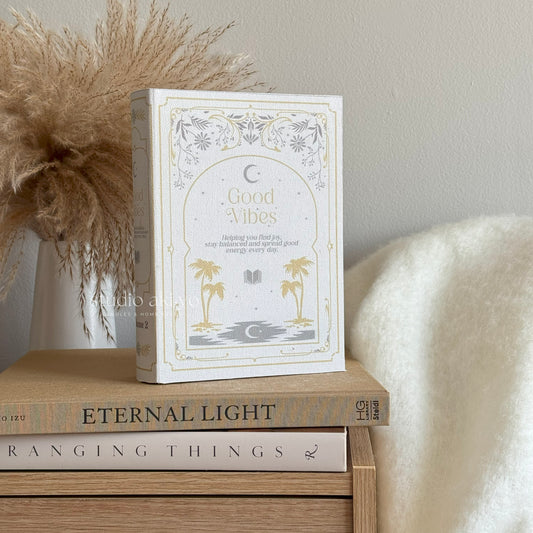 Book titled 'Good Vibes' on a wooden surface with decorative elements.