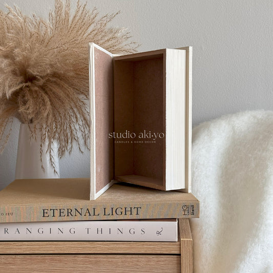 Open box with 'studio akiyo' branding on a surface with books and decorative elements.
