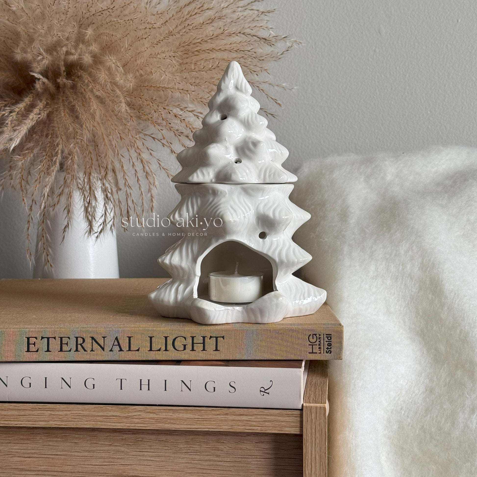 White ceramic tree-shaped oil diffuser on a stack of books .
