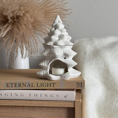 White ceramic tree-shaped oil diffuser on a stack of books .