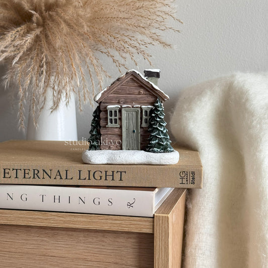 Winter Log cabin incense cone holder on top of books with a soft background