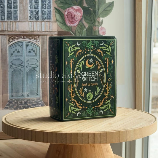 Green Witch book of spells on a wooden table with decorative elements in the background