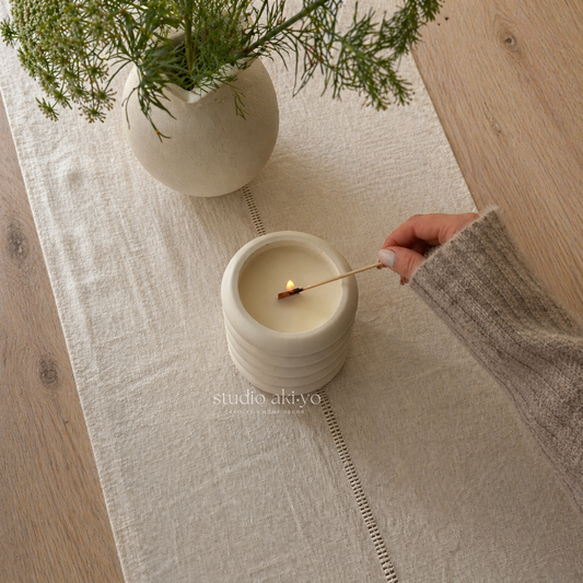 a hand lighting cloud nine candle from studio akiyo. 
