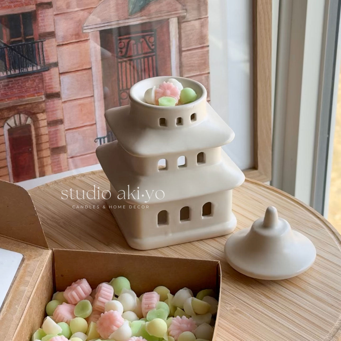 Pagoda wax melt burner with pastel-colored candies on a wooden surface, with 'studio akiyo' branding.