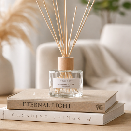Studio Akiyo reed diffuser on top of two books with a blurred background. Featuring natural reed sticks and wood lid.
