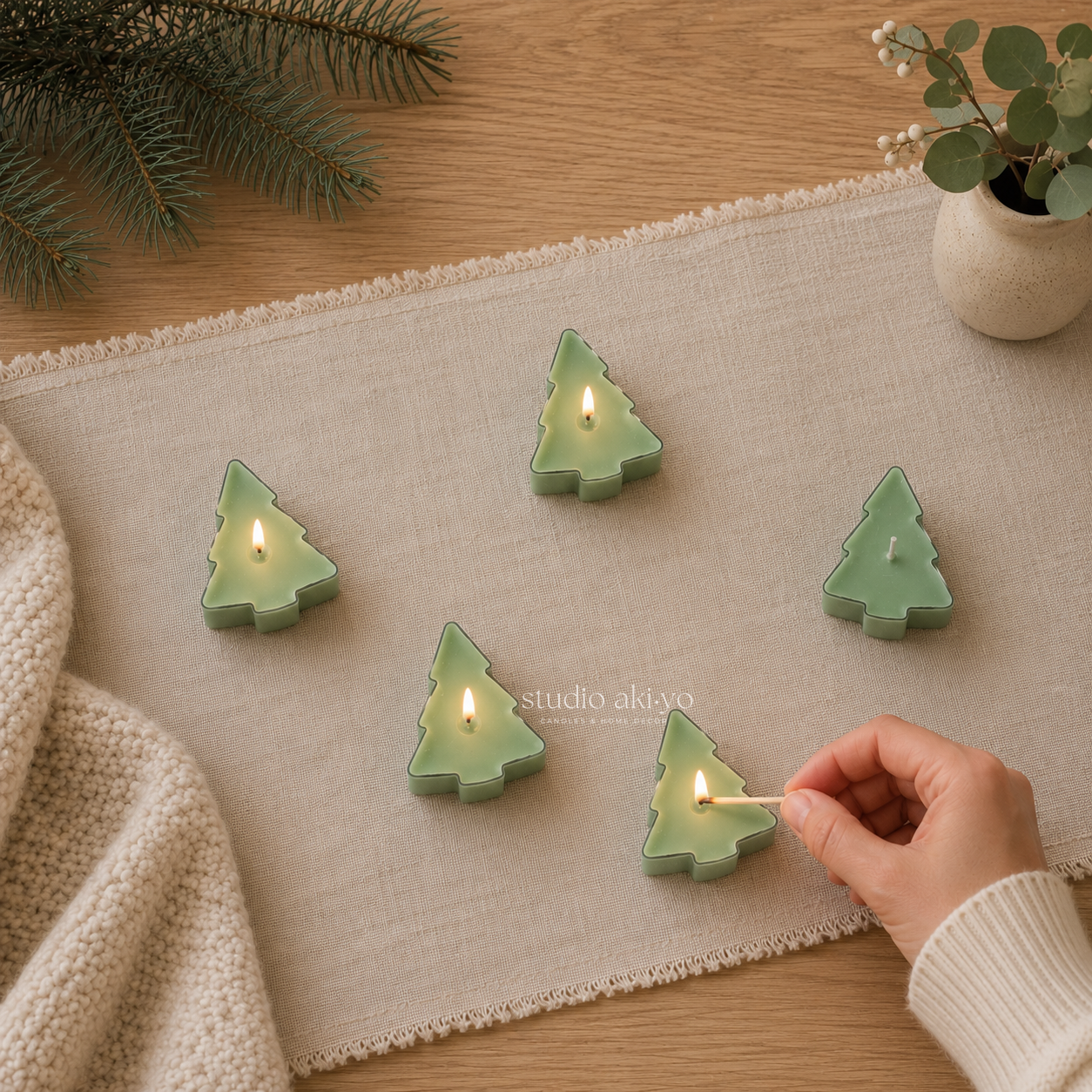Hand lighting Studio Akiyo winter wonderland green tree tealight scented candles.