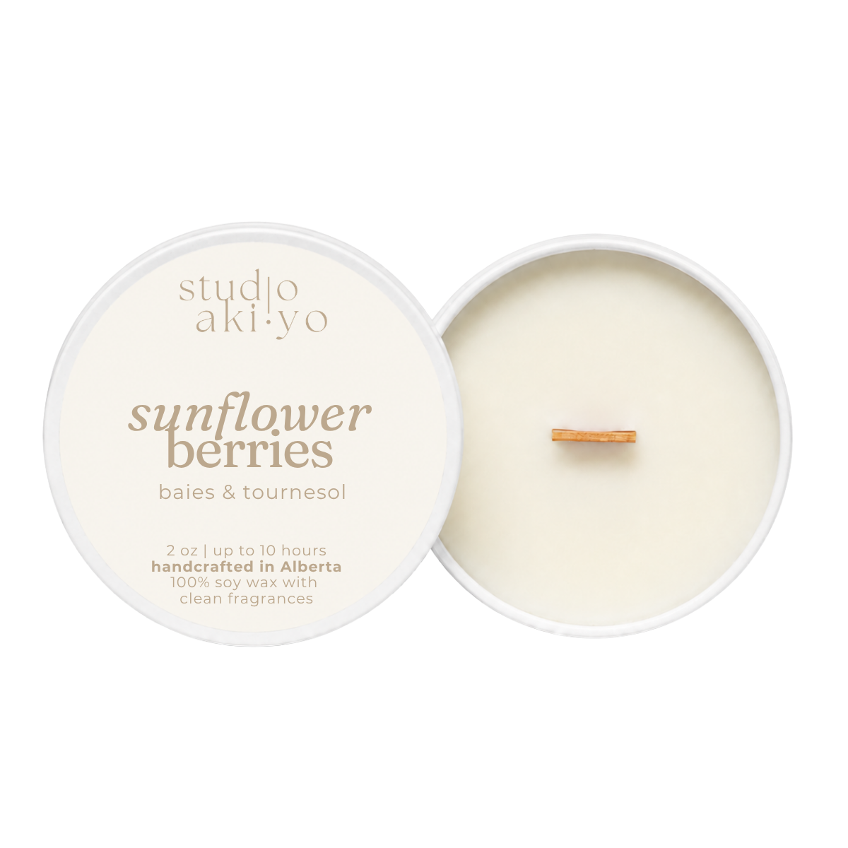 A round soy wax candle shown open with the cream-colored lid beside it on a white background. The lid reads 'studio aki·yo' and 'sunflower berries' with smaller text 'baies & tournesol' and '2 oz | up to 10 hours handcrafted in Alberta 100% soy wax with clean fragrances.