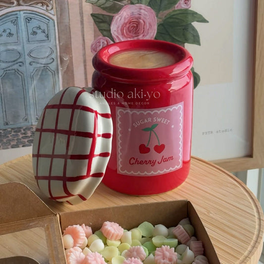 Red jar wax burner with cherry design labeled 'Sugar Sweet Cherry Jam' on a wooden surface with decorative elements.