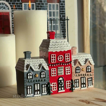 Decorative house models on a table with a candle in the background