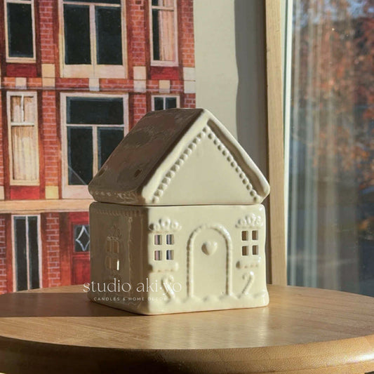 Ceramic house-shaped container on a wooden surface with a blurred background