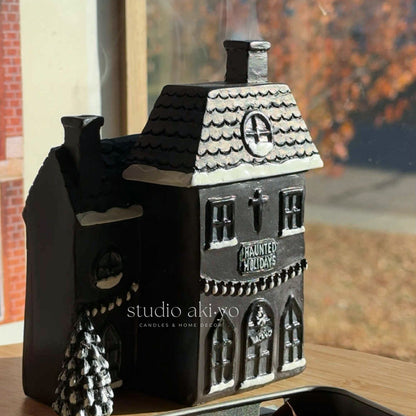Decorative haunted house candle holder with 'Haunted Holidays' text on a table.