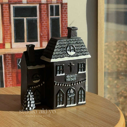 Decorative haunted house candle on a wooden surface with a blurred background