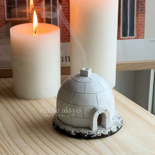 Igloo-shaped candle holder with a lit candle on a wooden surface, featuring 'studio aki-yo' branding.