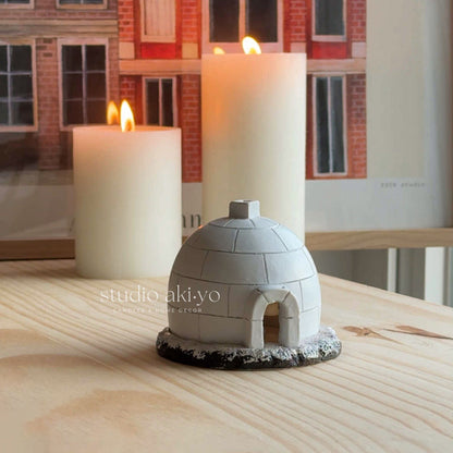Small dome-shaped object on a wooden surface with candles in the background