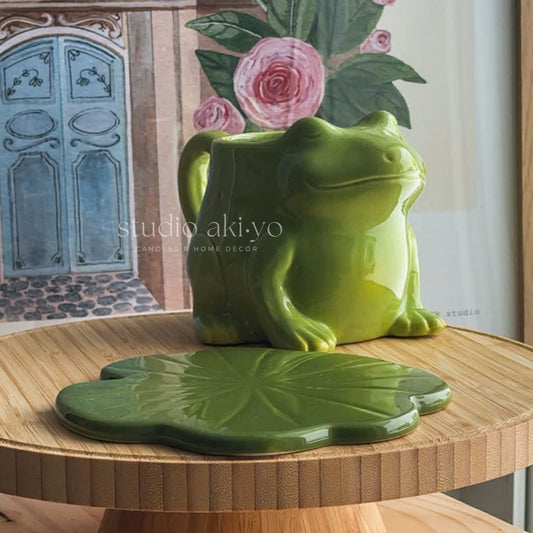Green ceramic frog on a lily pad with floral background